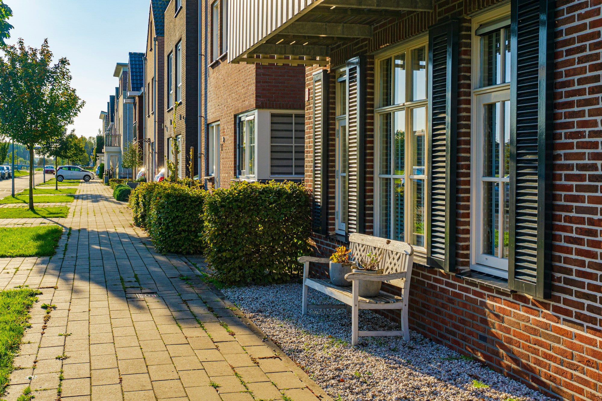 A row of brick terraced houses beside a pavement and planting in Almere, the Netherlands.