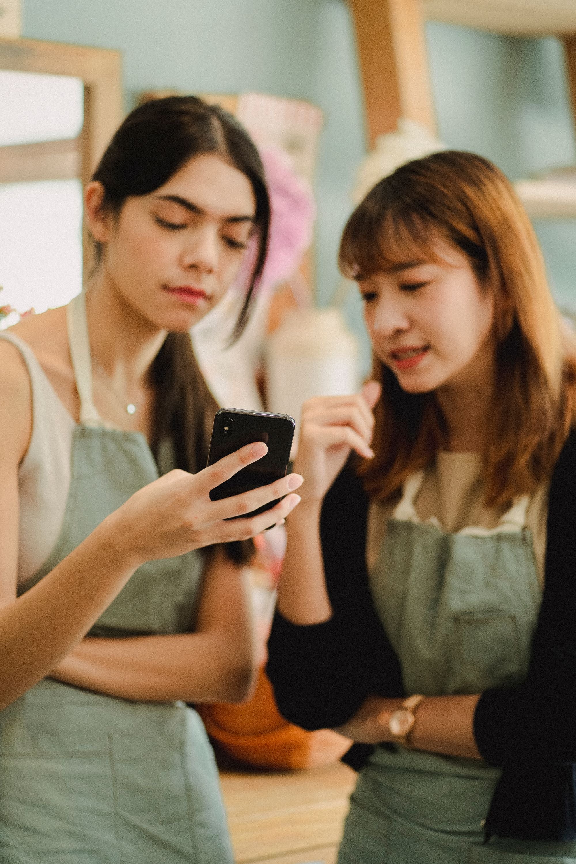 Two colleagues look at a smartphone together in a flower shop.