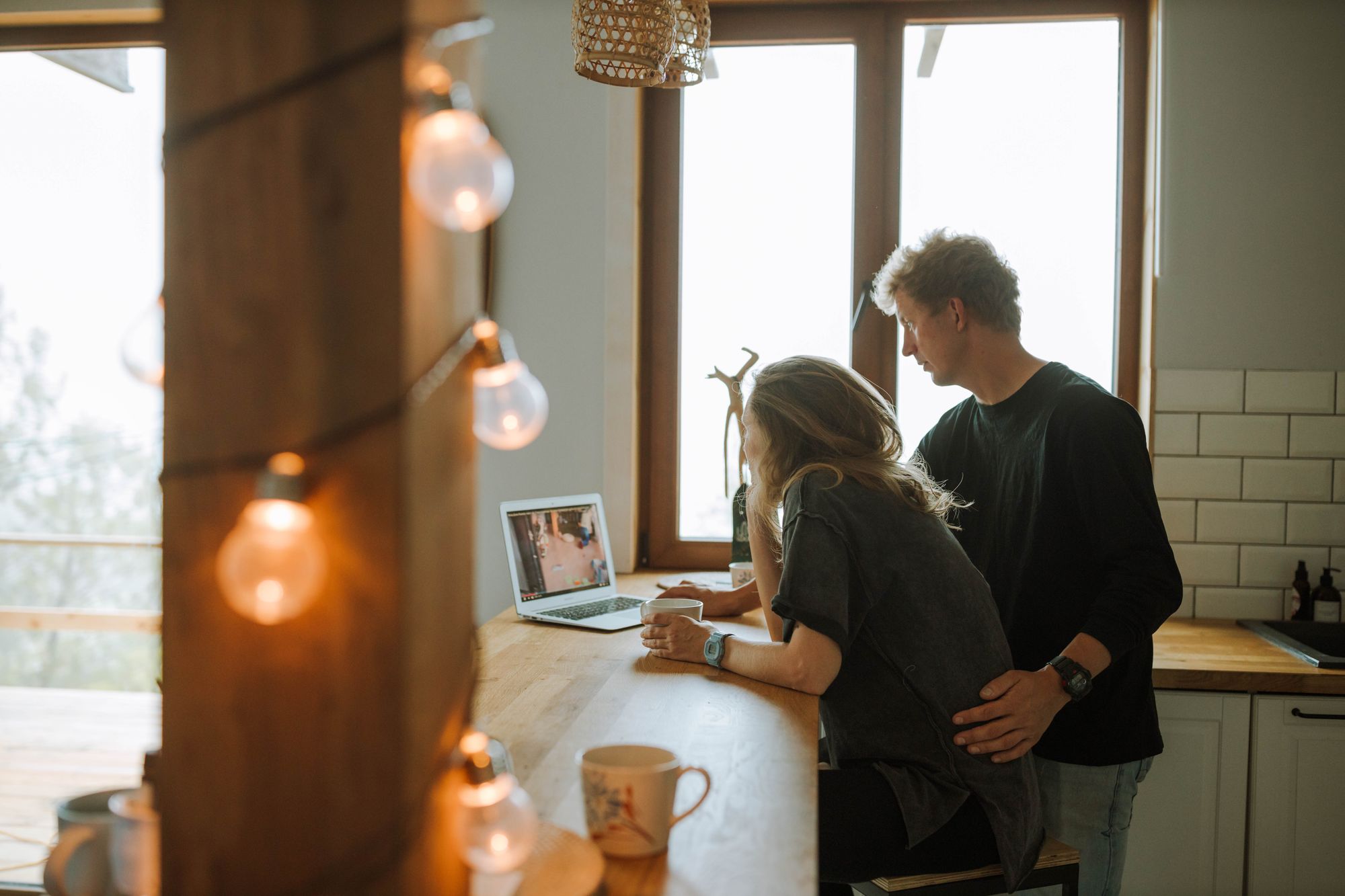 A couple look at a laptop together at their kitchen counter.