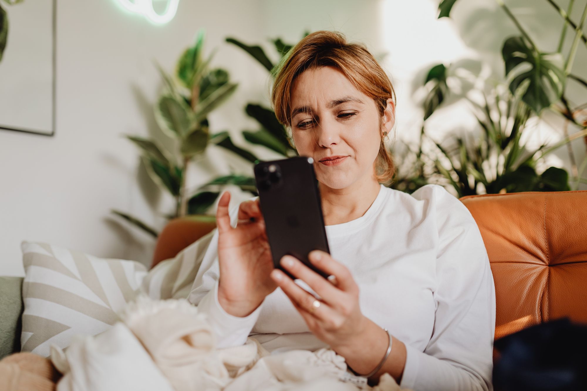 A woman uses her smartphone while sitting at home.